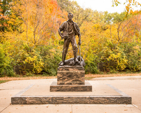 New Salem, IL - USA: Bronze statue of Abraham Lincoln as a young man carrying a book and axe with brilliant autumn colors in background. 
