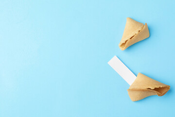Naklejka premium Tasty fortune cookie with prediction on light blue background, top view. Space for text