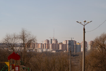 Fototapeta premium Empty playground with distant skyline backdrop, red play structure beside bare branches, quiet morning mood, imagined groundskeeper inspection, maintenance ready scene
