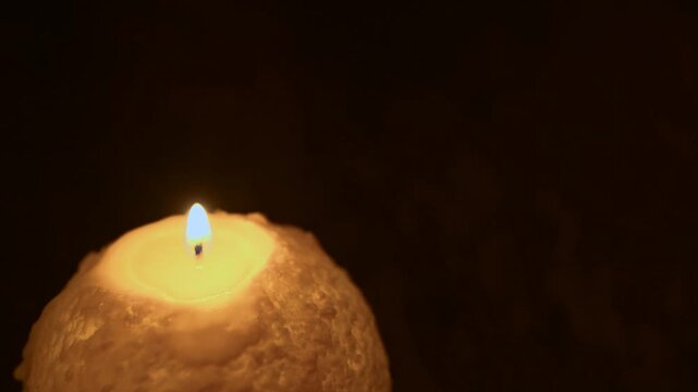 木のテーブルの上で炎が揺れる丸いキャンドル。