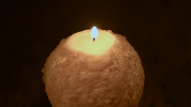 木のテーブルの上で炎が揺れる丸いキャンドル。