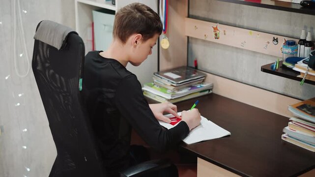 Young boy practices handwriting carefully. Young boy diligently practicing penmanship in peaceful study setting. Young boy focuses on handwriting practice at his desk in tranquil environment