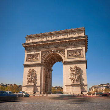 Arc de Triomphe framed by clear blue sky and bustling traffic in spring
