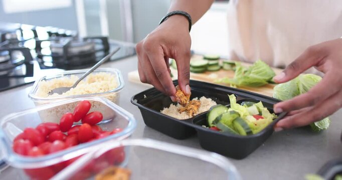 African American man reaching for jar at counter picking chicken placing on rice in tray portioning