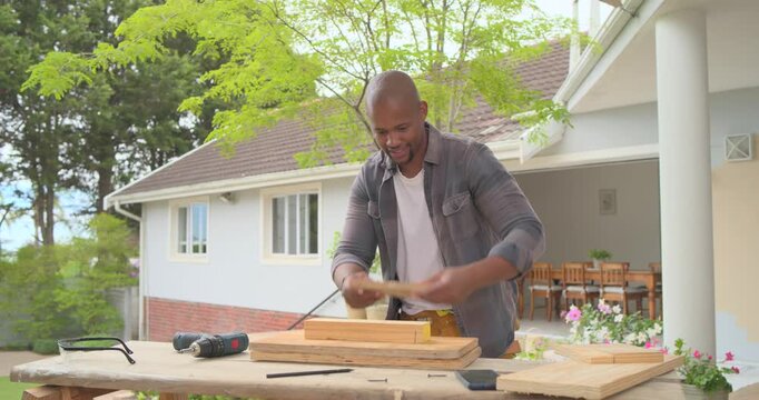 30s man assembling frame using green drill at yard bench after clamping boards, fastening screws