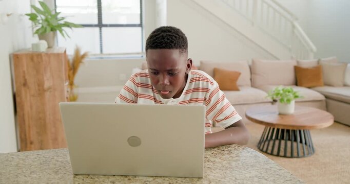 African male youth sitting at granite countertop reacting to laptop surprise, typing homework