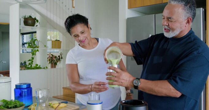 African American couple tasting shake after man lifting blender jar, pouring into glasses on island