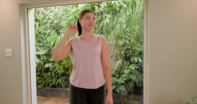 Camera is dollying in, woman is uncrossing and warming into laughter at window with planted wall