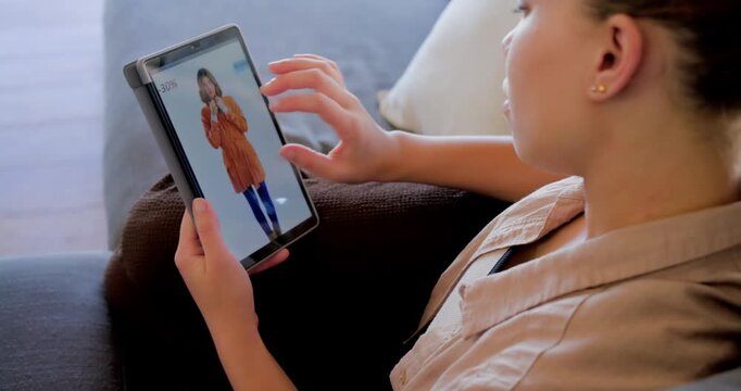 Viewing fullscreen red coat, African American woman tapping tablet on sofa and pinching, shopping