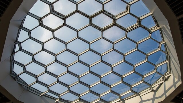 A modern glass ceiling with a honeycomb pattern and blue sky
