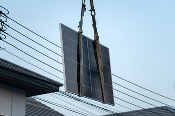 Obraz premium Solar cell panell is lifting by crane to installation on house roof with clearly blue sky as background. Technology equipment object, close-up.