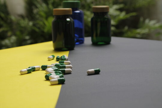 Capsulas verdes y blancas de fondo frascos coloridos.