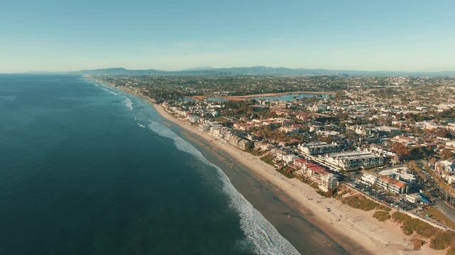 Aerial drone view of Carlsbad coastline with sandy beach, ocean waves and residential city along California Pacific coast
