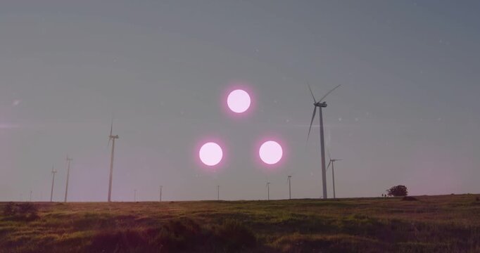 Late afternoon sunlight striking wind farm turbines creating pink flare triad peaking then fading