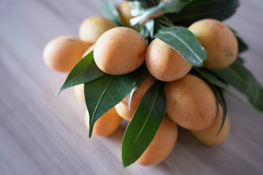 Close-up shot features a vibrant cluster of ripe Marian plums (also known as gandaria or plum mango).