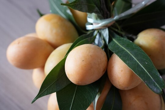Close-up shot features a vibrant cluster of ripe Marian plums (also known as gandaria or plum mango).