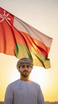 Young Omani man in traditional dress with national flag at sunset for cultural pride