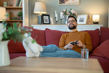 Man relaxing on sofa playing video game © Jelena