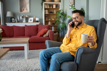 Obraz premium Young man talking on phone relaxing at home