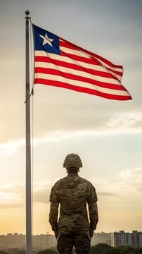 Black Liberian Male Soldier in Camouflage Uniform Standing at Attention Facing Flag at Sunset
