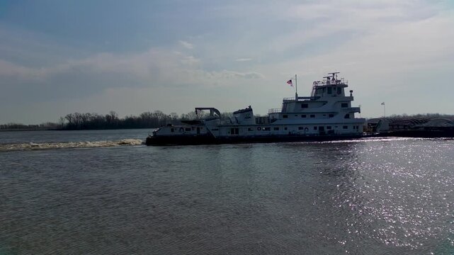 Tugboat pushing heavy industrial barges on the Mississippi River near rural Midwest town