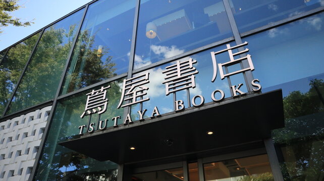 Tsutaya Books Daikanyama T-Site branch exterior featuring modern glass architecture facade with corporate logo signage and blue sky reflections - Tokyo, Japan, September 18, 2023