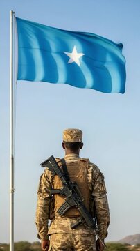 Back view of a Somali military officer in tactical gear looking at the blue star flag