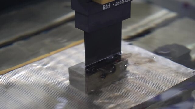 Slow motion operation of an EDM machine using a graphite electrode for high-precision spark erosion.