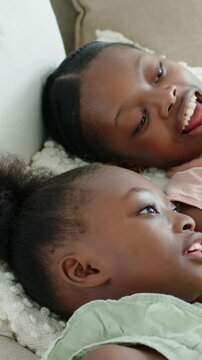 Vertical video: Talking teen holding phone on sofa, sharing clip, making pink, green tops smile