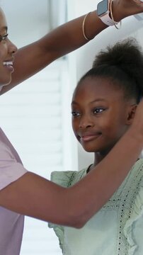 Vertical video: Measuring mom in mauve top raising phone over girl at white wall, checking watch
