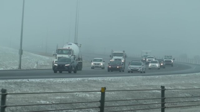 Vehicles trucks commute through heavy morning fog and mist on a snowy highway Calgary, Alberta, Canada.