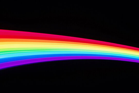 Vibrant rainbow arcs against deep black background.