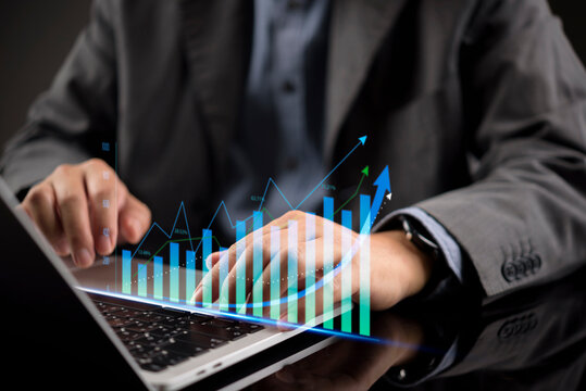 Businessman typing on laptop with digital stock market graph overlay. Financial trading, data analysis, and investment success. Business growth concept with futuristic virtual hologram chart.