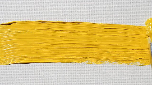 A close-up shot showcases a vibrant yellow paint stroke applied to a textured canvas, highlighting the artistic process and the tactile quality of the medium.