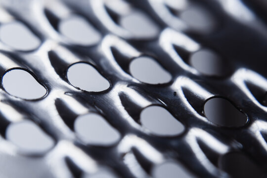 High angle macro shot of a stainless steel cheese grater surface with round holes