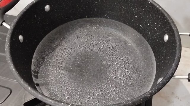 Boiling water in a pot on a gas stove, everyday kitchen activity with heat flame and simple cooking process at home.