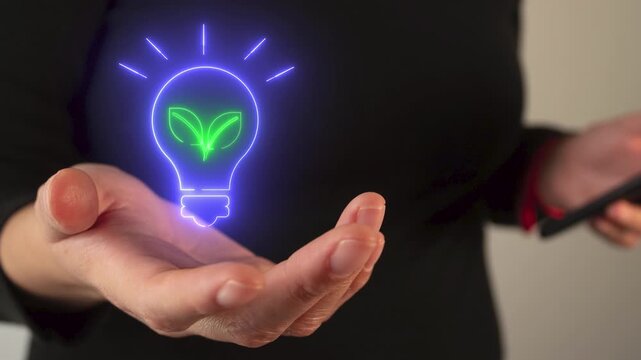 Businesswoman holding a virtual light bulb icon with a leaf inside