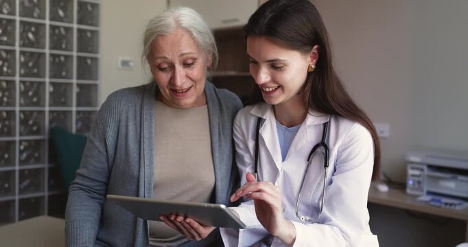 Senior patient and female doctor reviewing health test result, discussing telehealth app, medical information or diagnosis on digital tablet in clinic. Consultation, healthcare services technology use