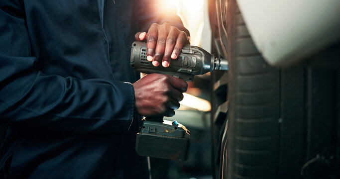 Man, hands and mechanic with power tool on tire for wheel change, repair or fix in workshop. Male person, engineer or technician with equipment for bolts, vehicle maintenance or car calibration test