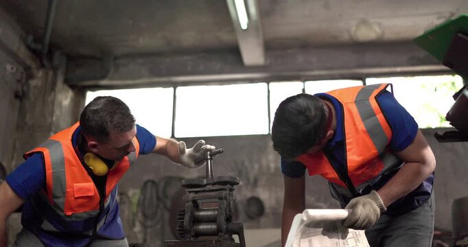 Factory technicians inspect machinery and discuss repair steps in a metal workshop, showing teamwork, maintenance coordination, safety, and industrial support.
