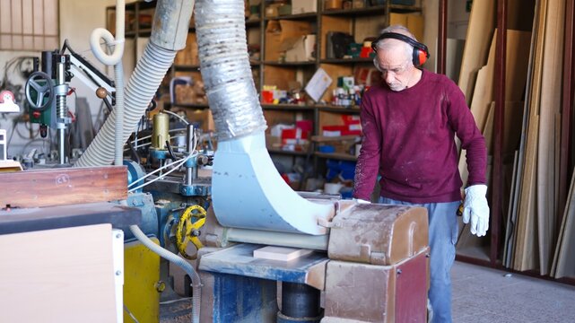 Senior craftsman working on thicknesser machine in workshop