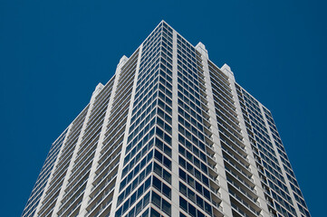 Fototapeta premium A sleek skyscraper stands tall against a clear blue sky