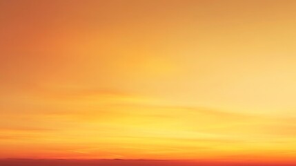 Fototapeta premium A vibrant orange and yellow sunset sky with warm hues and soft clouds
