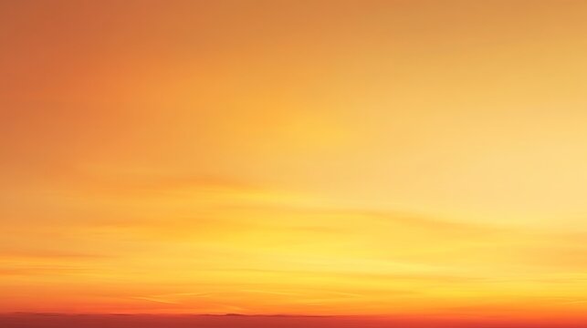 A vibrant orange and yellow sunset sky with warm hues and soft clouds