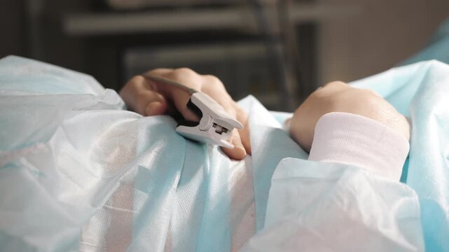 Close up of patient hand with pulse oximeter monitoring oxygen saturation during medical care in clinic healthcare monitoring concept.