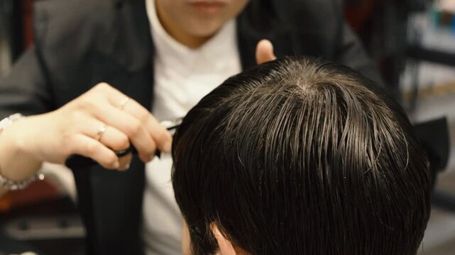 Professional hairstylist cutting male hair with comb and scissors