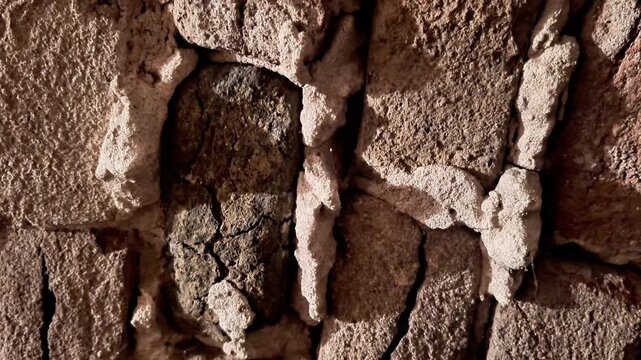 Close up of aged brick wall with visible cracks, rough surfaces, and worn mortar gaps, highlighting rugged texture and weathered detail of deteriorating masonry structure