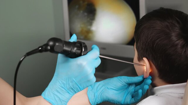 Doctor performing ear examination with endoscope on child in clinic close up ENT diagnostic procedure healthcare indoors.