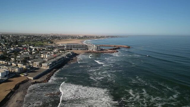Aerial footage captures Sea Point, Cape Town, showcasing stunning coastal cityscape, waves, beachfront, and vibrant urban architecture under clear blue skies. Explore breathtaking views from above.