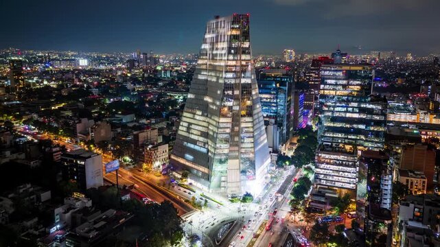 Aerial night timelapse of modern glass skyscraper and city lights on Insurgentes Avenue, Mexico City